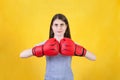 Young woman with red boxing gloves stands ready in a fighting stance, punching her fists. Portrait of determined girl prepared for Royalty Free Stock Photo