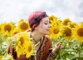 Young woman with red burgundy hair, wearing boho hippie clothes, standing in the middle of yellow sunflowers field. Creative close Royalty Free Stock Photo