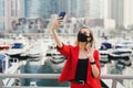 Young woman in red business suit wearing protective face mask of black color taking a selfie Royalty Free Stock Photo