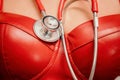 Young woman in red corset and black leather pants with a phonendoscope. Sexy brunette nurse in red and black costume Royalty Free Stock Photo