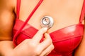 Young woman in red corset and black leather pants with a phonendoscope. Sexy brunette nurse in red and black costume Royalty Free Stock Photo