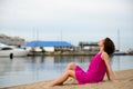 Young woman in a red dress ans curly hair sit on the water coast Royalty Free Stock Photo