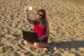 Young woman in red dress with computer and smartphone on the beach. Freelance and downshifting concept. Royalty Free Stock Photo