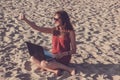 Young woman in red dress with computer and smartphone on the beach. Freelance and downshifting concept. Royalty Free Stock Photo