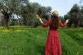 Young woman in hat and red dress enjoying summer and nature in yellow flower field at sunset, harmony and healthy lifestyle
