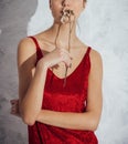 Young woman in red dress portrait holding a dry flower hiding her mouth