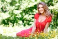 Young woman in red dress sitting on grass