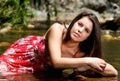 Young woman in red dress sitting in river water in summer Royalty Free Stock Photo