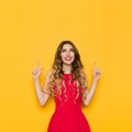 Young Woman In Red Dress Is Smiling, Pointing And Looking Up. Royalty Free Stock Photo