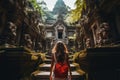 A young woman in a red dress is standing in front of the temple of Angkor Wat, A tourist woman with a backpack on vacation,