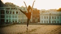 Young woman in red dress standing in the graceful balet pose on the roof - modern buildings on the background - bright