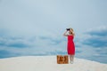 Woman in red dress with suitcase looking in binoculars Royalty Free Stock Photo