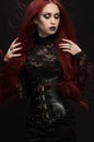 Young woman with red hair in black gothic costume