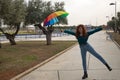 Young woman, red hair, freckles, with a rainbow umbrella, dancing happily, in an outdoor park. Concept joy, happiness, well-being