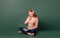 A young woman with red hair sitting reads a book and listens to music Royalty Free Stock Photo