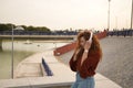 Young woman, red-haired, freckled, with red sweater and white headphones, listening to music, in an outdoor park . Concept song, Royalty Free Stock Photo