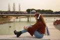 Young woman, red-haired, freckled, with red sweater and white headphones, sitting and concentrating, listening to music, in an Royalty Free Stock Photo