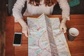 Young woman red head girl traveller reading looking at paper map in cafe