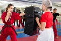 Young woman in red kimono launching blows on punch shield