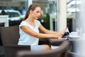 Young woman with red lips reads a newspaper sitting in a cafe