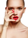 Young woman with red lips and red nails, touching her face