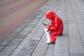 A young woman in a red raincoat pulled a hood over her head to hide from the rain. Sitting on the steps, Smoking, looking at the Royalty Free Stock Photo