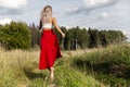A young woman in a red skirt runs in the field. Back view. Power of nature