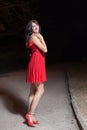 Young woman in red sleeveless dress walking in night park Royalty Free Stock Photo