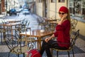 Young woman with red suitcase talking on the phone sitting at a table. Royalty Free Stock Photo