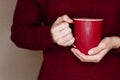 Young woman in red sweater is holding red cup of tea or coffee Royalty Free Stock Photo