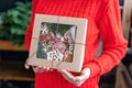 Young woman in red sweater holding in his hand Christmas gift, homemade gingerbread. Biscuits in festive packaging. Royalty Free Stock Photo