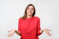 Young woman in red sweater standing disorientated bewildered isolated on gray wall background. Decision making concept.