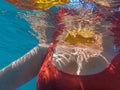 Young woman in a red swimsuit and maple leaves swim in the sea in autumn