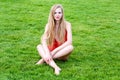 Young woman in red swimsuit sunbathing on the grass. Summer leisure, outdoors in the park at luxury resort. Royalty Free Stock Photo