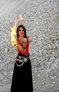 Young woman in a red top, long black skirt and ethnic jewelery smiling holding in hands two flaming torch