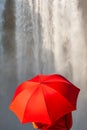 Young Woman WIth Red Umbrella In Front of a Waterfall