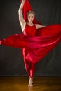 Young woman in red unitard swirling red fabric in studio. Royalty Free Stock Photo