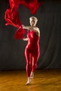 Young woman in red unitard swirling red fabric in studio. Royalty Free Stock Photo