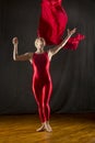 Young woman in red unitard swirling red fabric in studio. Royalty Free Stock Photo