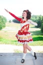 Young woman in red and white irish dance dress and wig posing