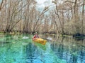 Young woman in red-yellow kayak paddling on clear waters of the Itchetucknee River in late winter, Florida