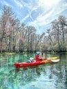 Young woman in red-yellow kayak paddling on clear waters of the Itchetucknee River in late winter, Florida