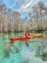 Young woman in red-yellow kayak paddling on clear waters of the Itchetucknee River in late winter, Florida