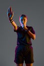 Young woman referee blowing whistle with serious expression against grey studio background in neon light Royalty Free Stock Photo