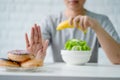 Young woman rejecting junk food or unhealthy food such as donut and choosing healthy food such as green apple and salad for her Royalty Free Stock Photo