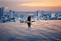 Young woman relax in swimming pool on roof top during amazing sunset and enjoy city view Royalty Free Stock Photo