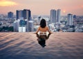 Young woman relax in swimming pool on roof top during amazing sunset and enjoy city view Royalty Free Stock Photo