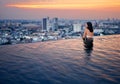 Young woman relax in swimming pool on roof top during amazing sunset and enjoy city view Royalty Free Stock Photo