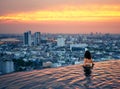 Young woman relax in swimming pool on roof top during amazing sunset and enjoy cityscape Royalty Free Stock Photo