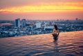 Young woman relax in swimming pool on roof top during amazing sunset and enjoy cityscape Royalty Free Stock Photo